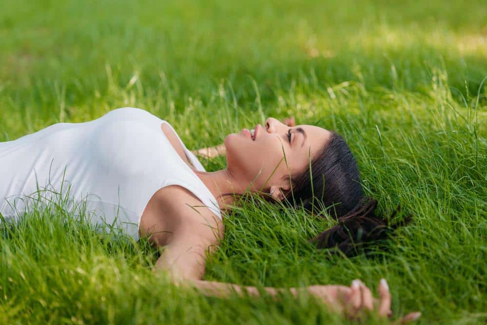 practising grounding - a woman lying on the grass connected with the earth